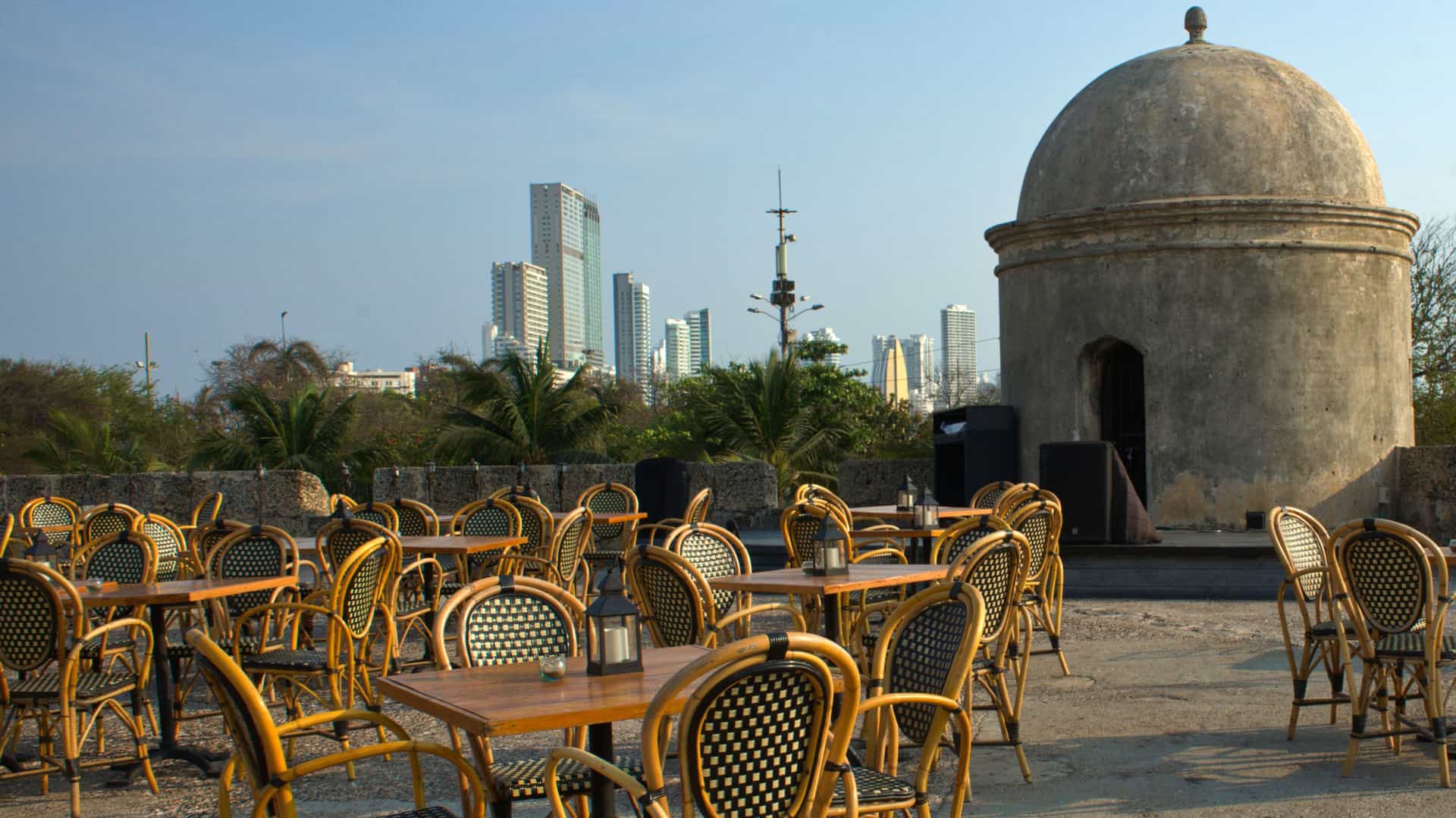 This photo showcases the elegant, open air dining experience at a traditional walled city Cartagena restaurant, likely featuring a courtyard setting. The colonial architecture, with its exposed stone arches, lush hanging plants, and warm ambient lighting, creates a romantic and sophisticated atmosphere for fine dining.