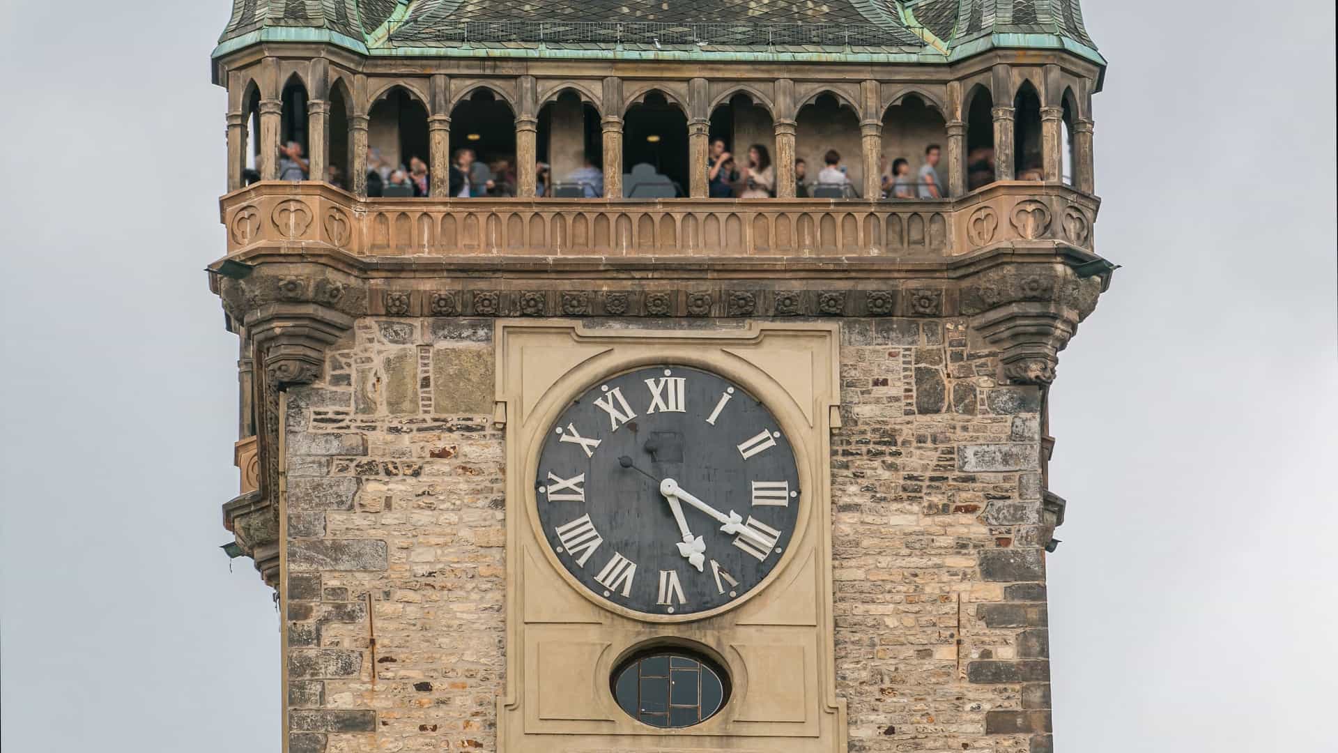 A photographic sequence or timelapse of the Old Town Hall Tower and its Astronomical Clock (Orloj) in Prague, Czech Republic. The scene captures the movement of clouds or the changing light over the Gothic tower and its intricate medieval clock face, highlighting the dynamic atmosphere of the Old Town Square.