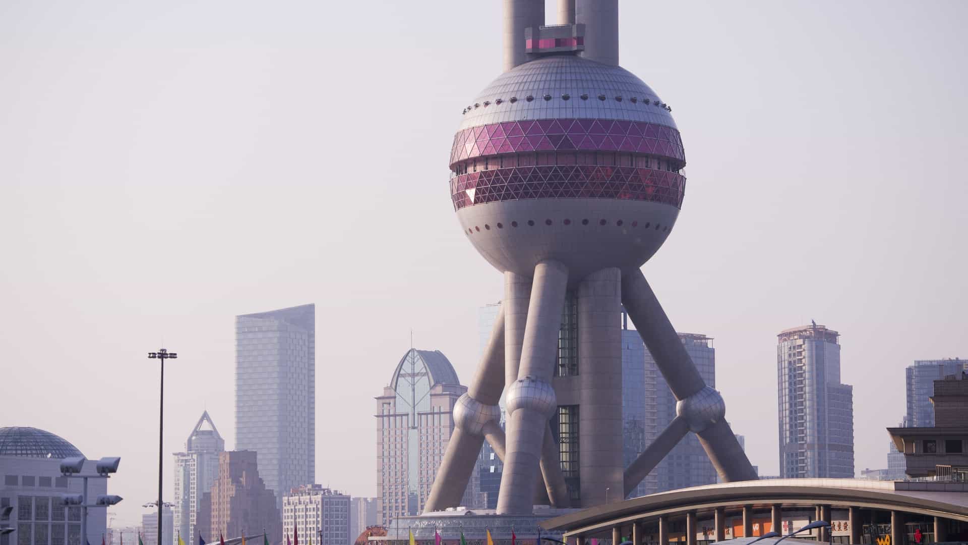 The Oriental Pearl Tower, Shanghai's iconic landmark, is a futuristic TV tower featuring multiple spheres of different sizes stacked vertically on three main supports, rising high above the modern skyscrapers of the Lujiazui financial district.