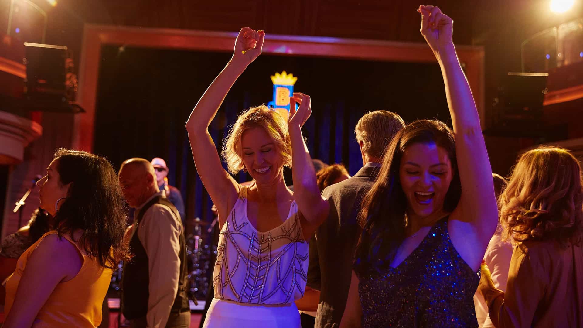 Guests dance joyfully with their hands raised in front of the stage at B.B. King's Blues Club aboard a cruise ship.