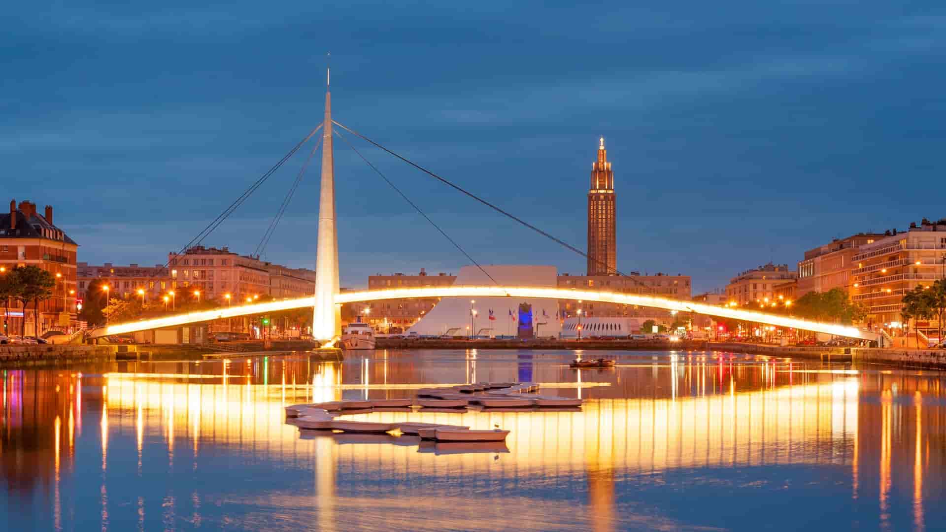 Illuminated bridge and city buildings at dusk in Le Havre, France.