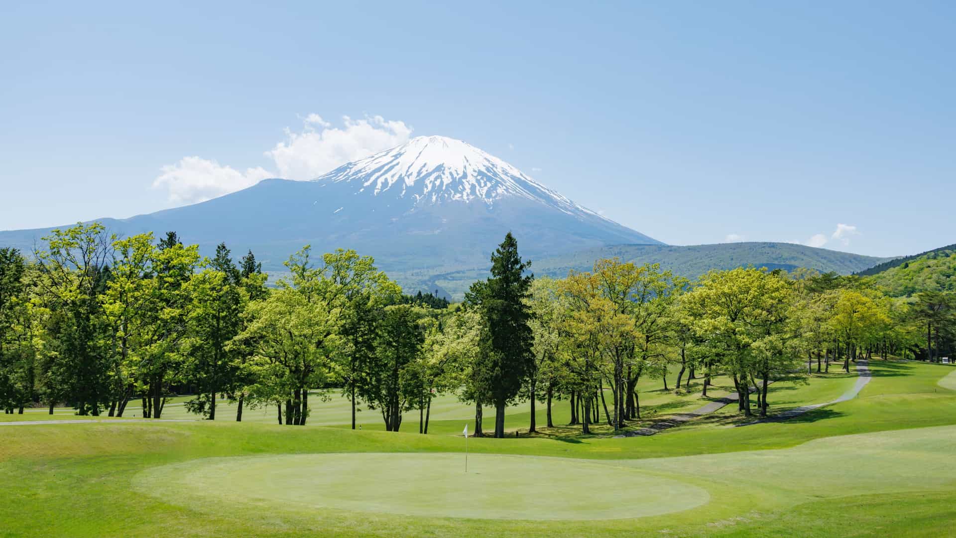 A lush green golf course with Mount Fuiji in the background.