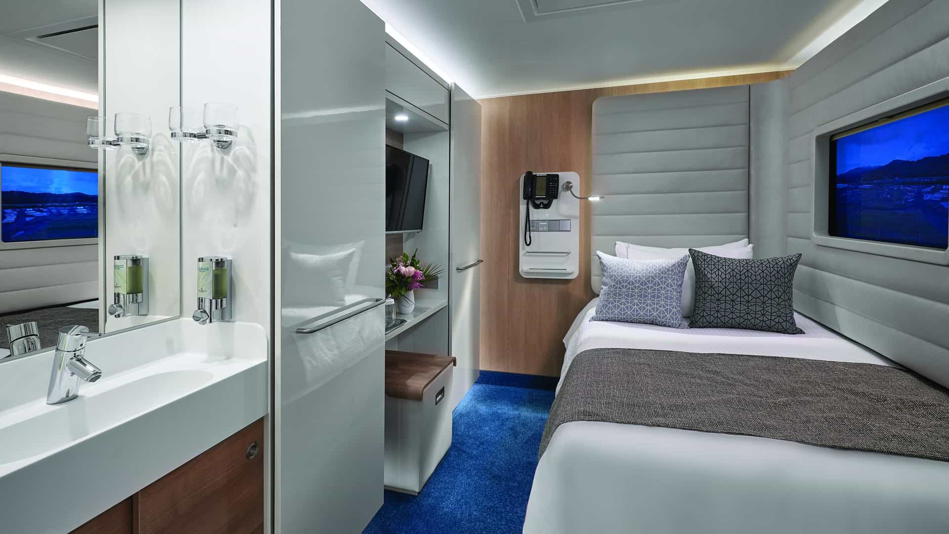 Studio on Norwegian Bliss with a bed, sink and mirror, wall-mounted TV and a framed screen showing a hillside view.