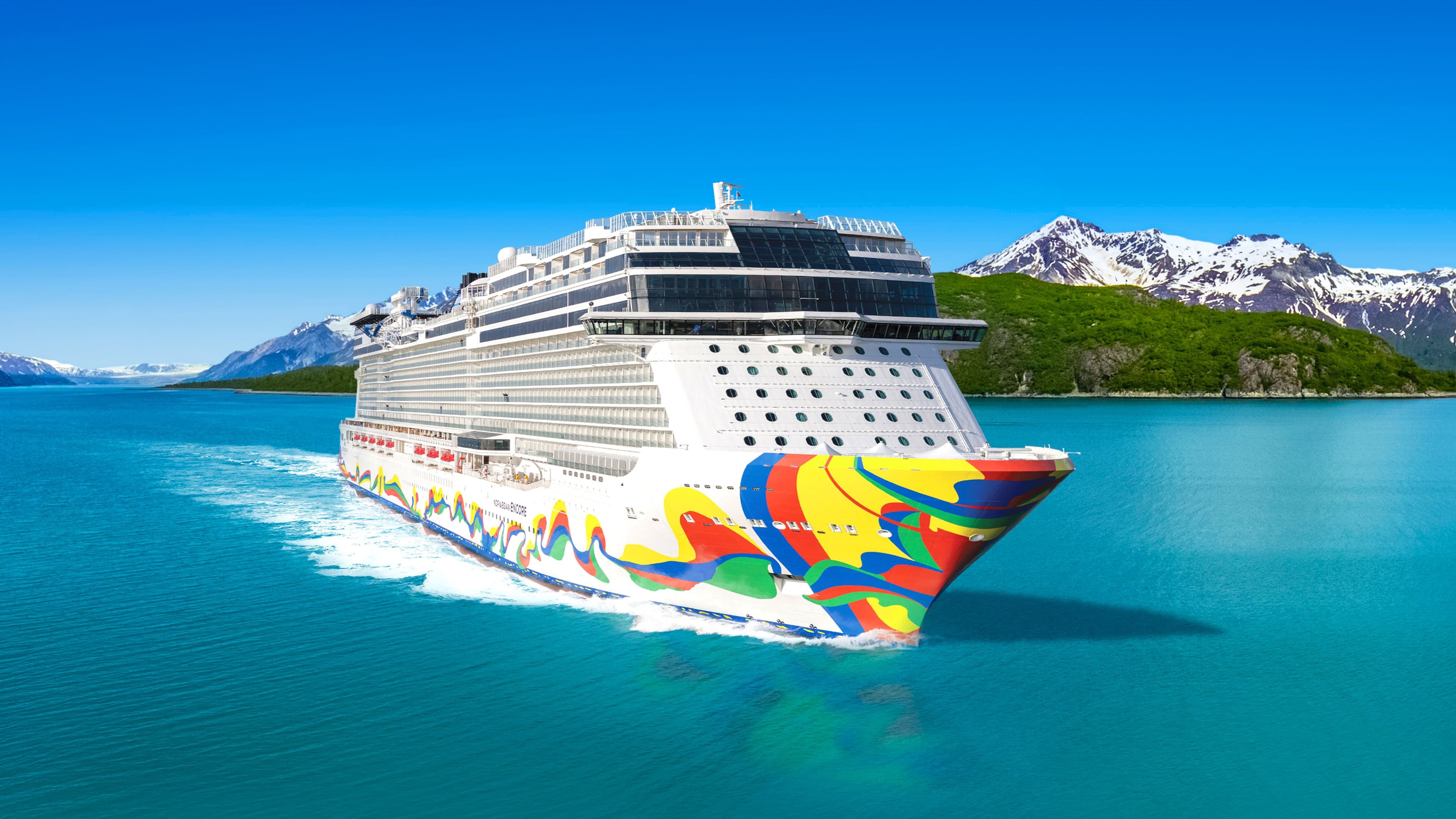 Norwegian Encore sailing past snow-capped mountains in Alaska.
