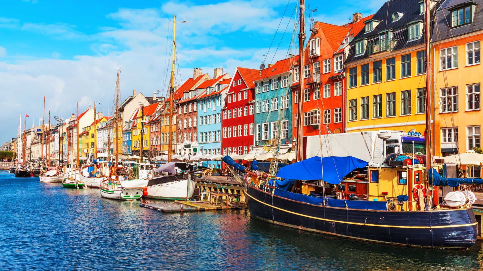 Oceania Cruises in Copenhagen, Denmark: Explore the iconic colorful houses and historic boats lining the picturesque Nyhavn canal, a vibrant port of call in Northern Europe.