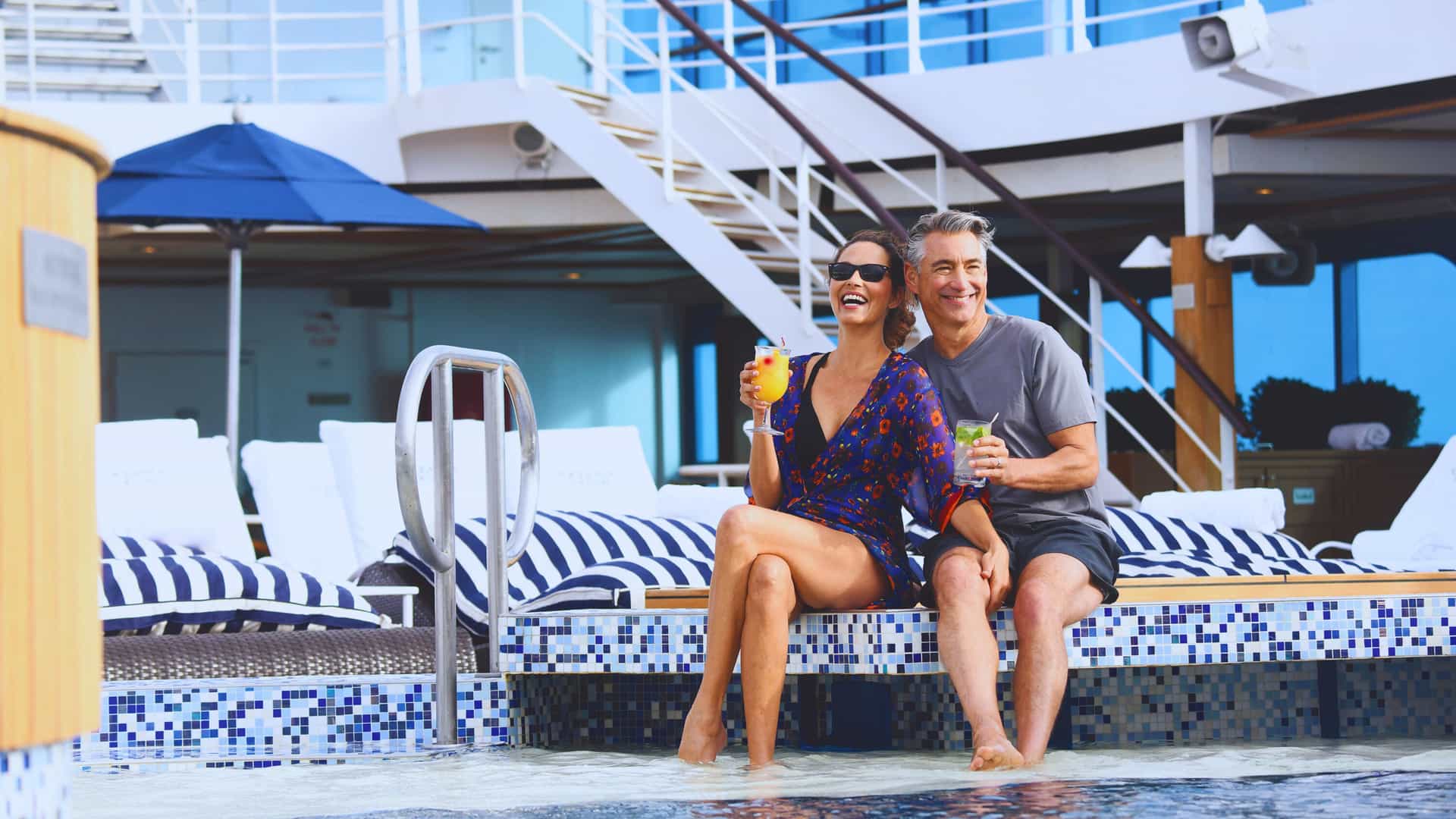 A couple sits in a pool on an Oceania cruise ship.