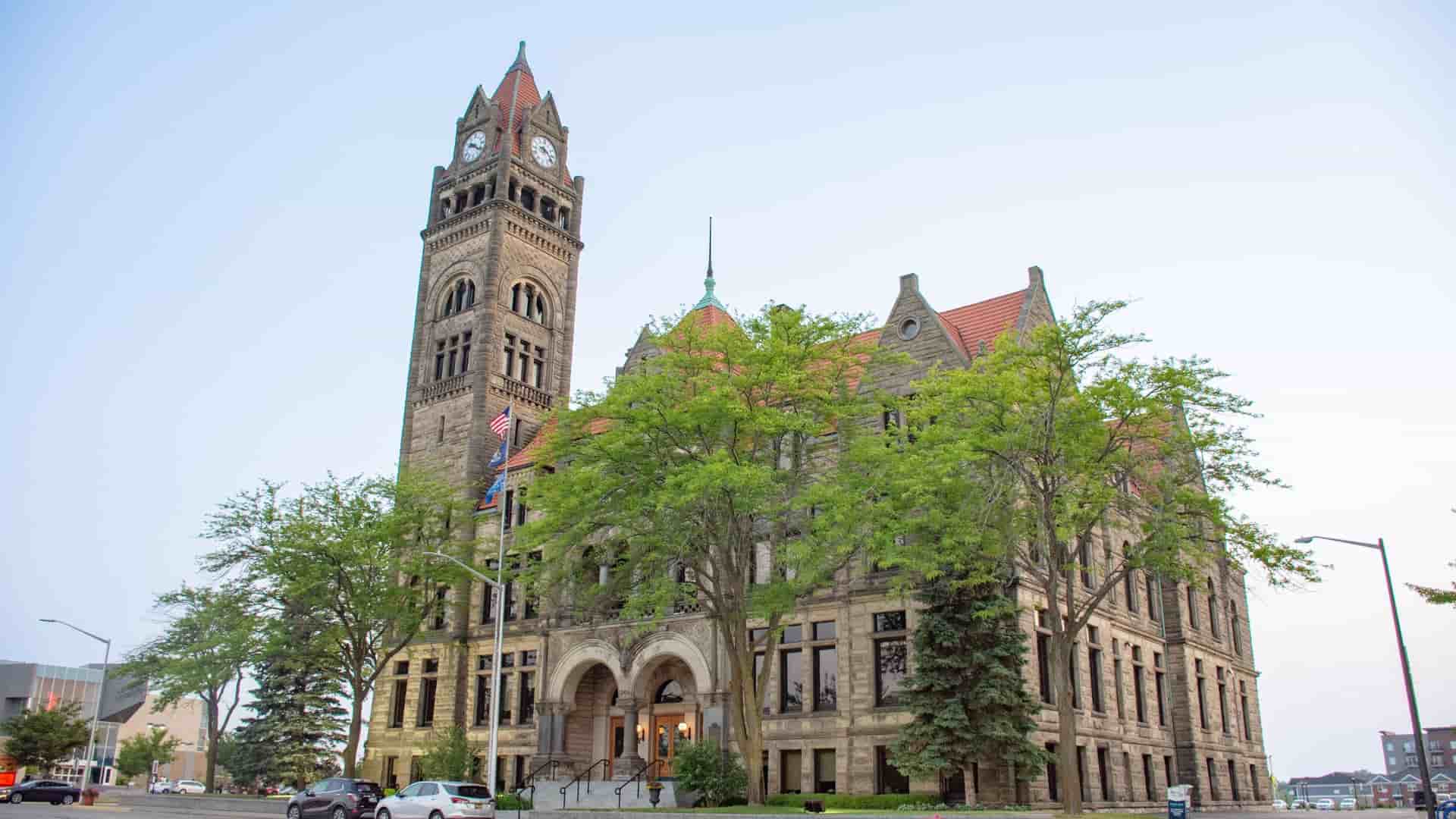 A grand, historic stone building, the Bay County Courthouse, stands tall with a clock tower in Bay City, Michigan.