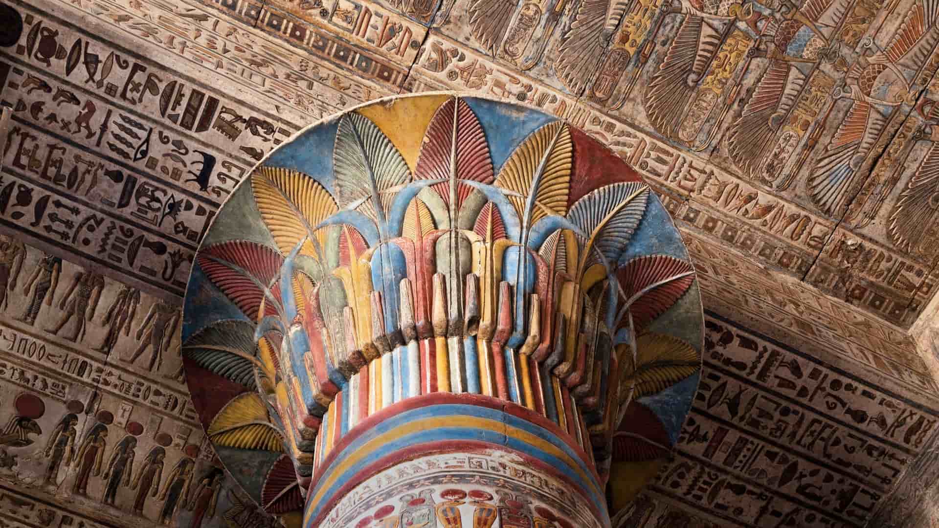 A vibrant, detailed close-up shot of a massive, painted column capital inside the ancient Temple of Esna, showcasing well-preserved Egyptian hieroglyphs and colorful decorations.