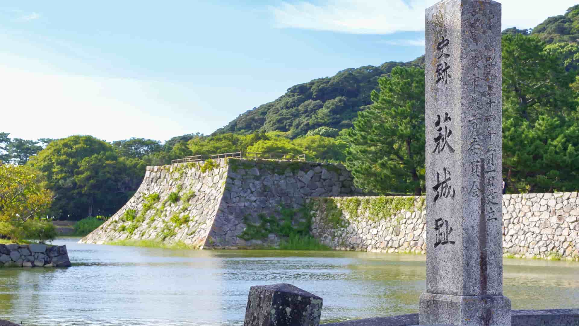 A stone monument and the fortified moat wall of the ancient Hagi Castle ruins in Hagi, Japan.