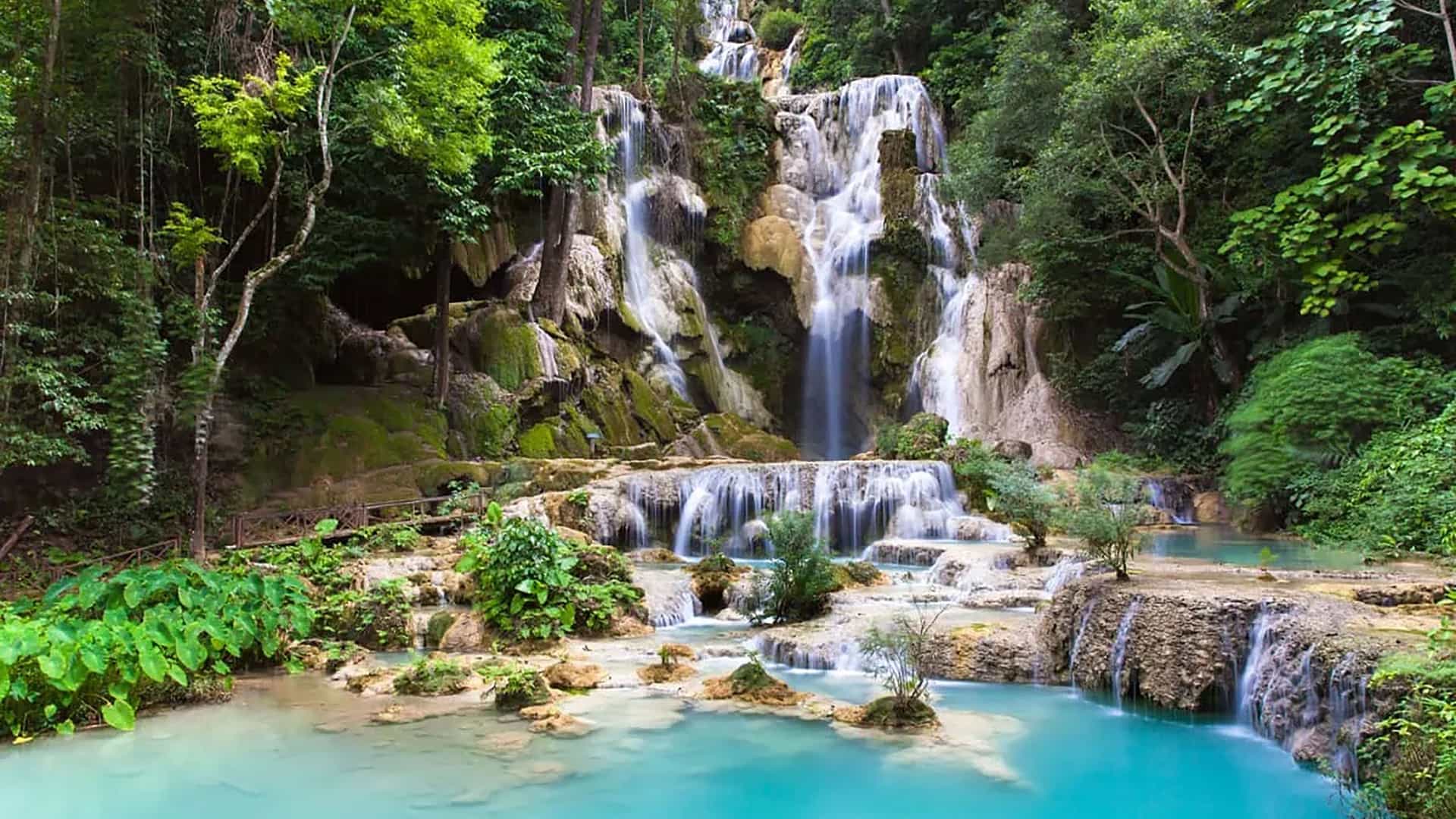 "A beautiful long-exposure shot of the multi-tiered Kuang Si Falls in Luang Prabang, Laos, with its stunning turquoise pools and lush green forest surroundings. "