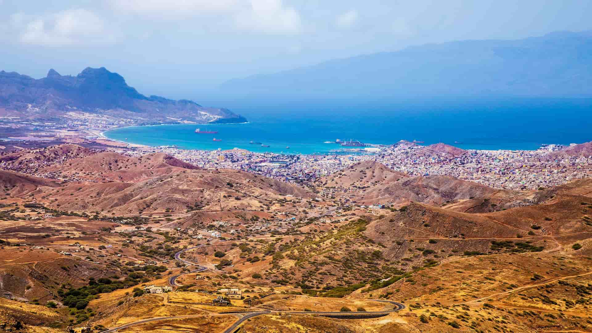 A breathtaking high-angle view of the large harbor and city of Porto Grande, São Vicente, Cape Verde, nestled between arid mountains and the serene Atlantic Ocean.