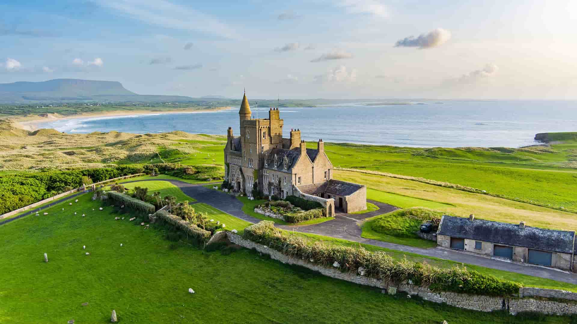 "An aerial view of the iconic Mullaghmore Castle in Sligo, Ireland, a historic castle on a lush green hilltop overlooking the Atlantic Ocean. "