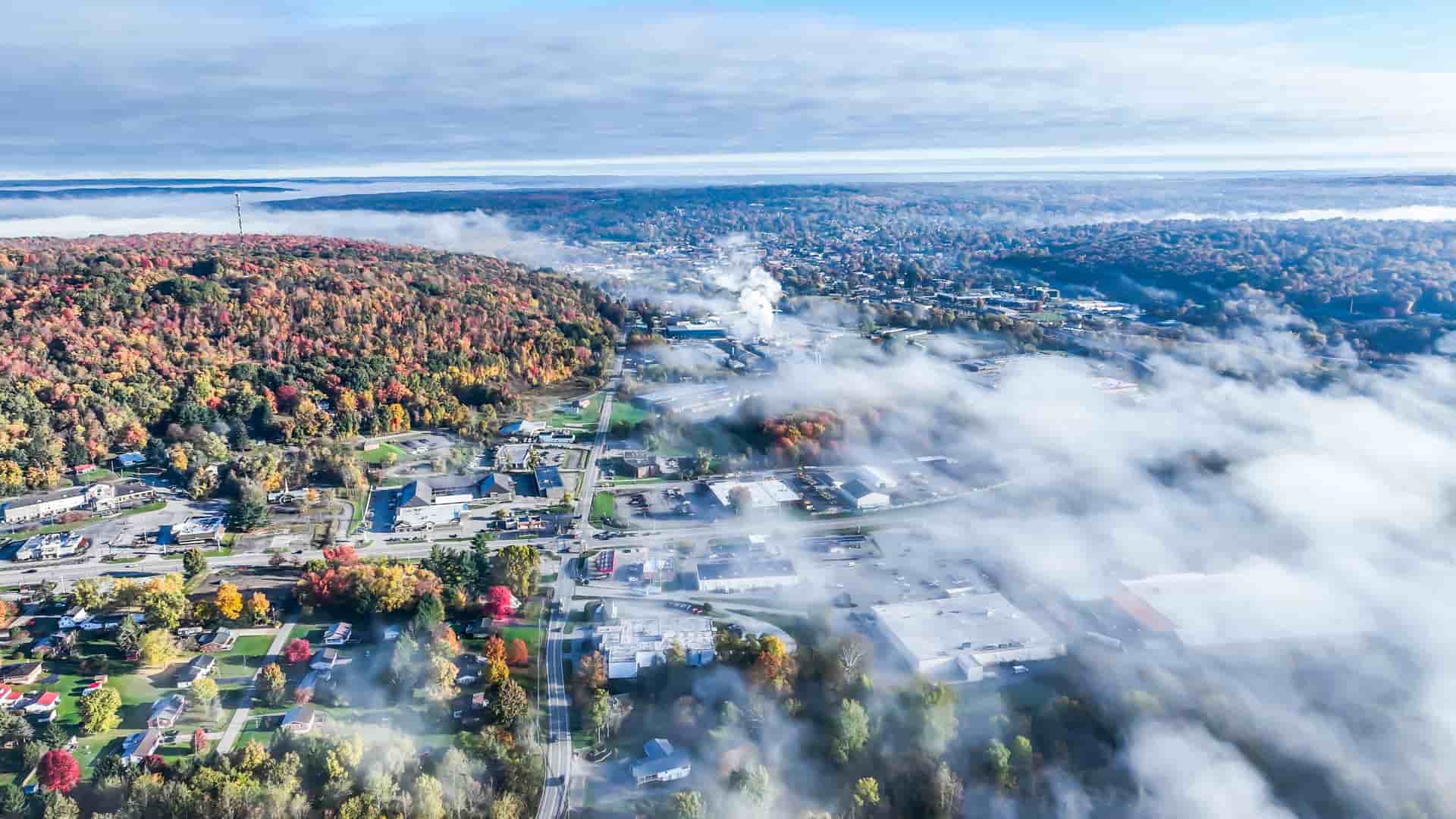 An aerial view of Stratton, Vermont, on a misty autumn day, with colorful fall foliage surrounding the town buildings.