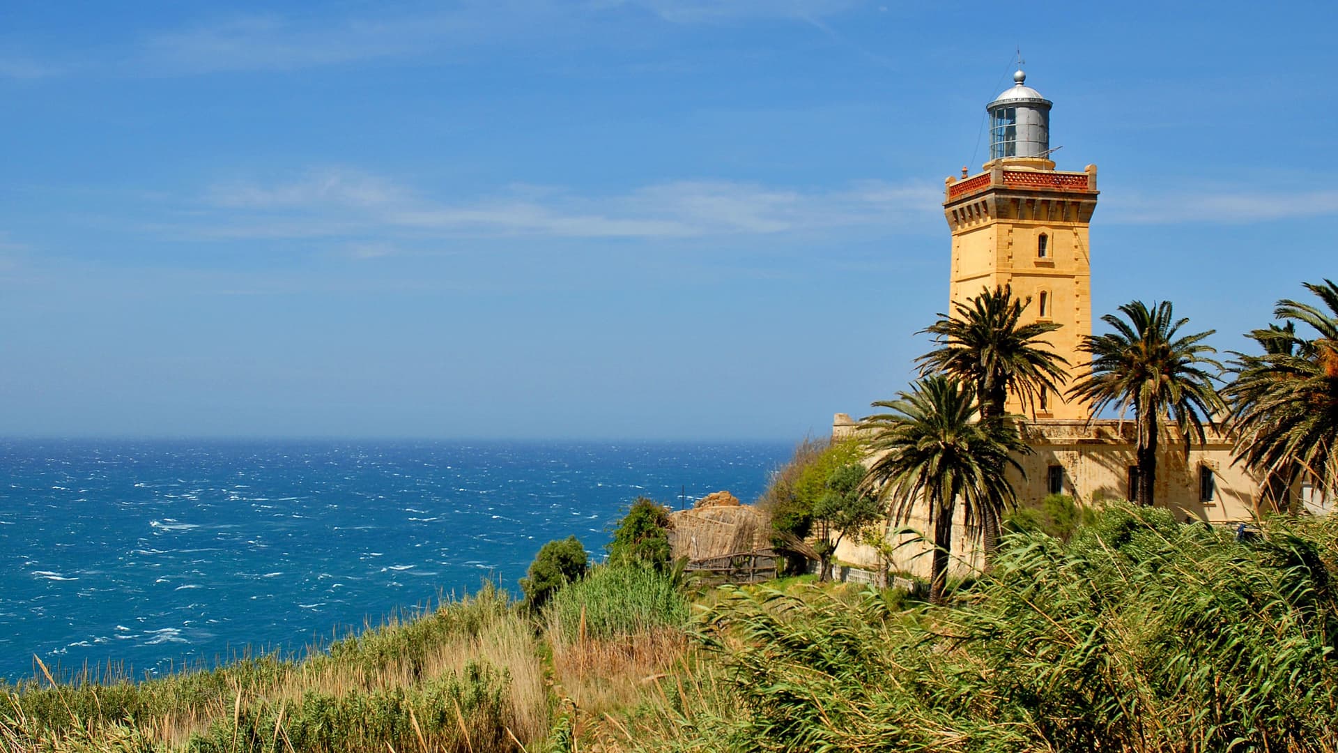A picturesque view of the historic Cape Spartel Lighthouse on a cliff overlooking the Atlantic Ocean near Tangier, Morocco.