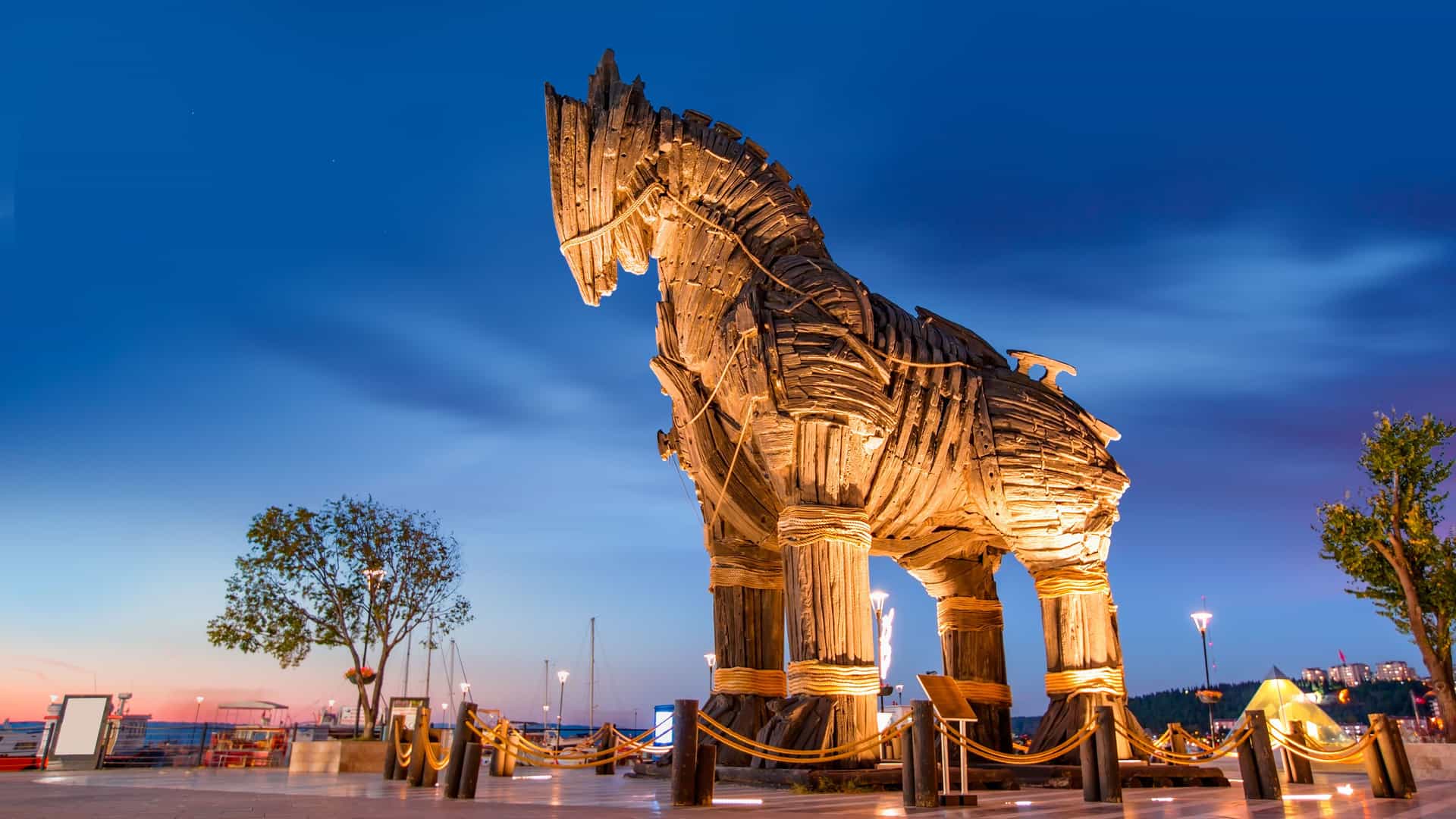"A towering wooden Trojan Horse sculpture stands illuminated at dusk in Çanakkale, Turkey, overlooking the Aegean Sea as a modern tribute to the ancient city of Troy. "
