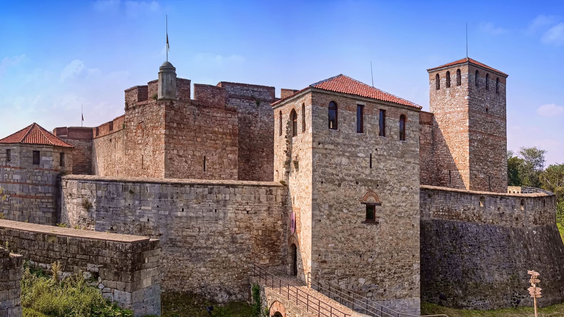 A historic view of the Baba Vida Fortress, a medieval castle with thick stone walls and towers, a major landmark in Vidin, Bulgaria, under a blue sky.