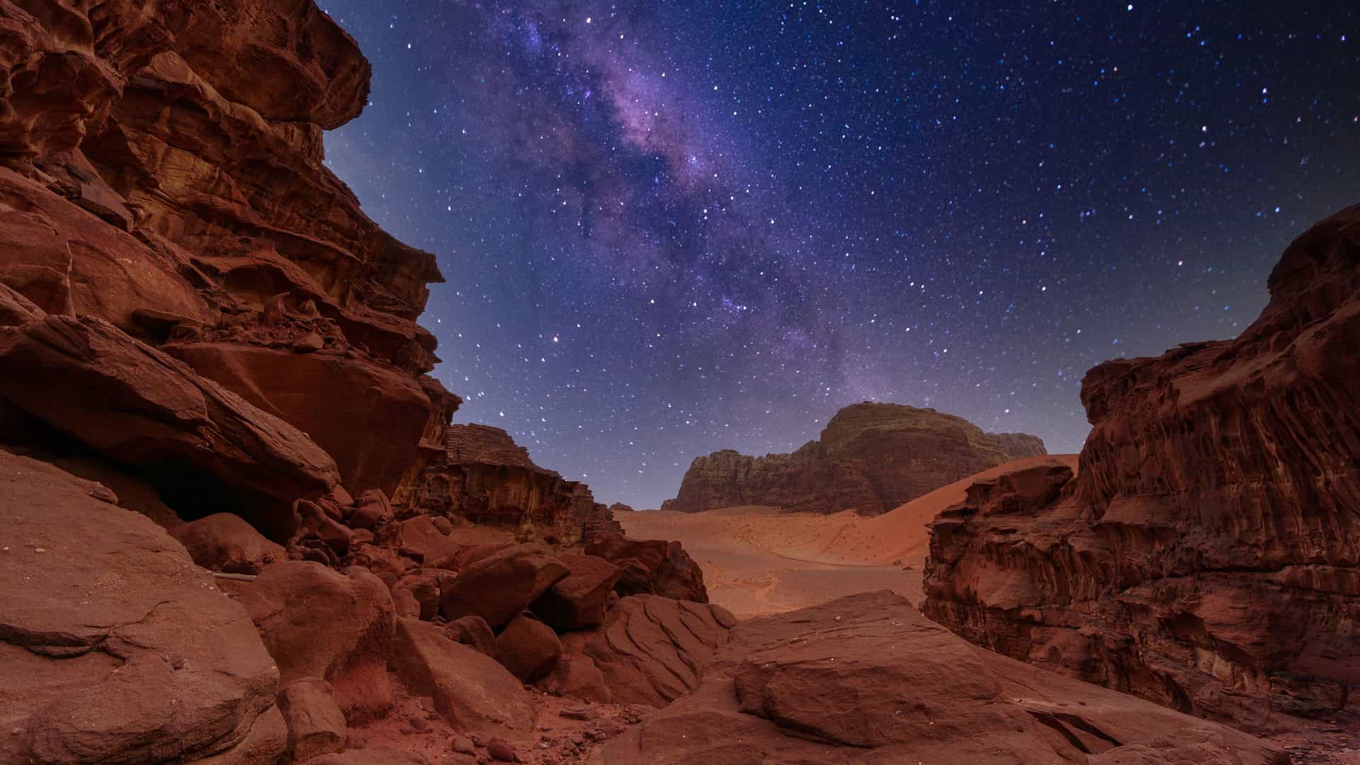 "A dramatic night sky with the Milky Way visible over the red sandstone mountains of the Wadi Rum desert in Jordan. "