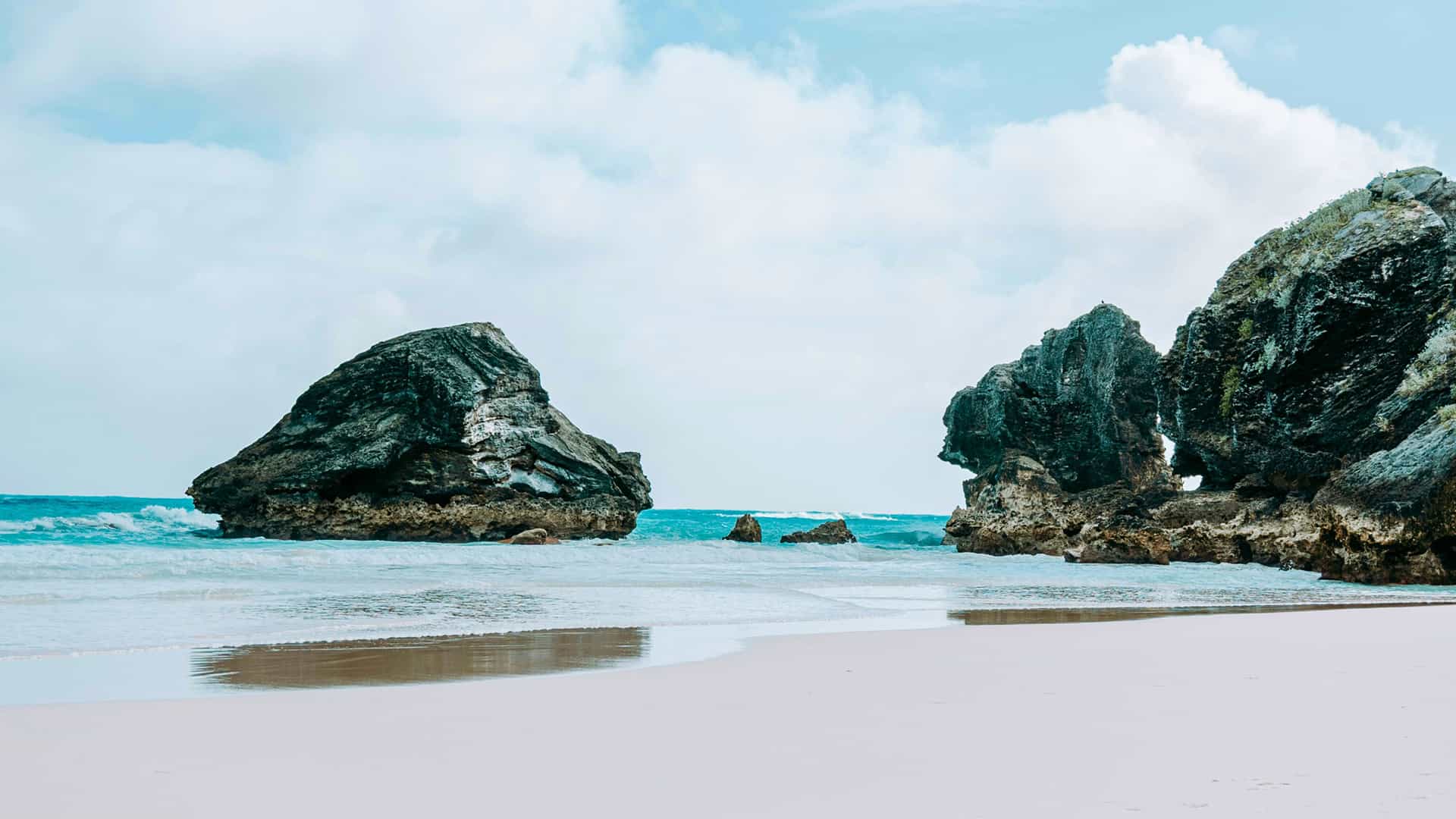 A beautiful Bermuda beach with distinctive rock formations meeting the clear turquoise ocean, a featured destination on Princess Cruises voyages.