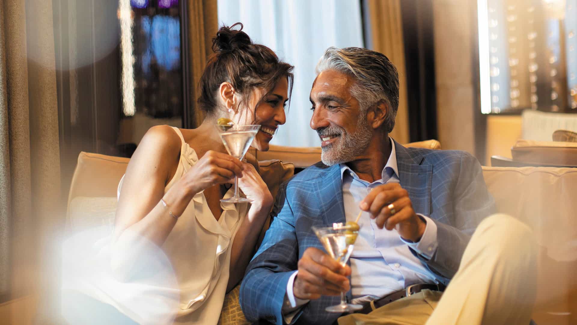 A couple enjoys cocktails in the elegant Horizon Lounge aboard a Regent Seven Seas ship.