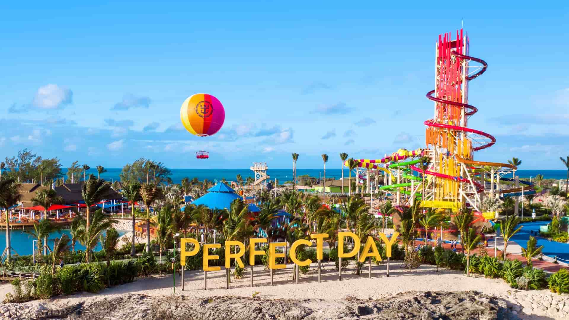The welcome sign with a hot air balloon, and the Daredevil Tower waterslides in the background at Cococay, Royal Caribbean's private island.