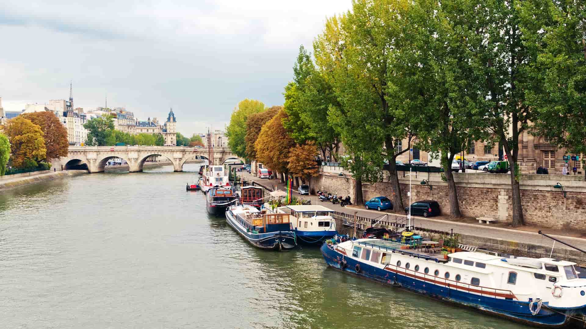 A scenic view of the Seine River with several boats floating on its surface.