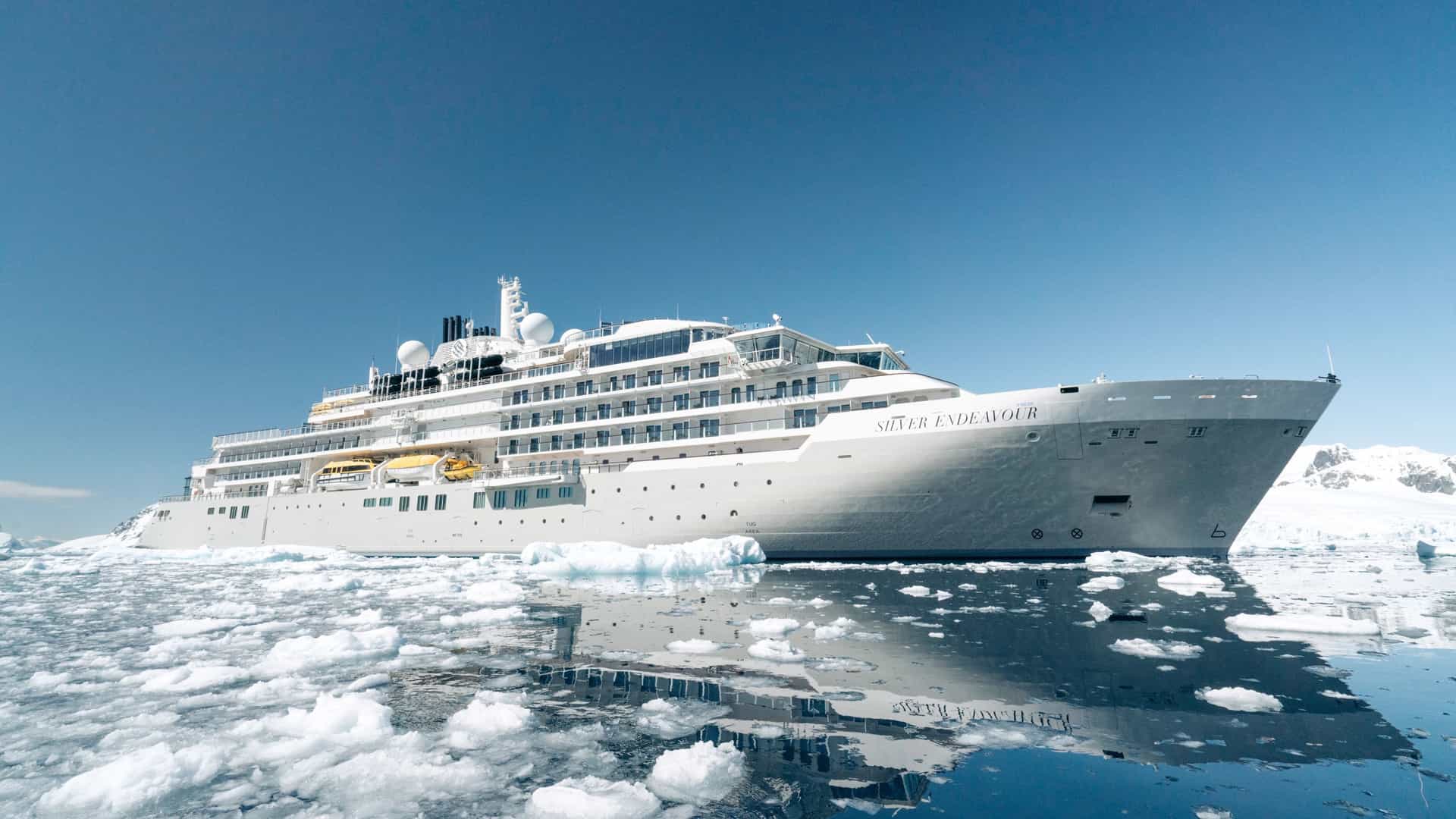 The Silver Endeavour ultra-luxury expedition cruise ship navigating through floating ice fields near Petermann Island, Antarctica.