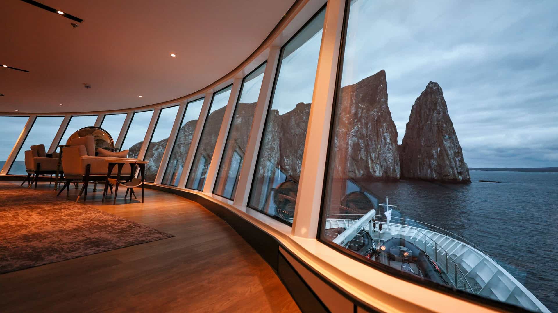 The elegant interior of the Observation Lounge on the Silver Origin cruise ship, offering panoramic views of Kicker Rock (Leon Dormido) in the Galapagos Islands.