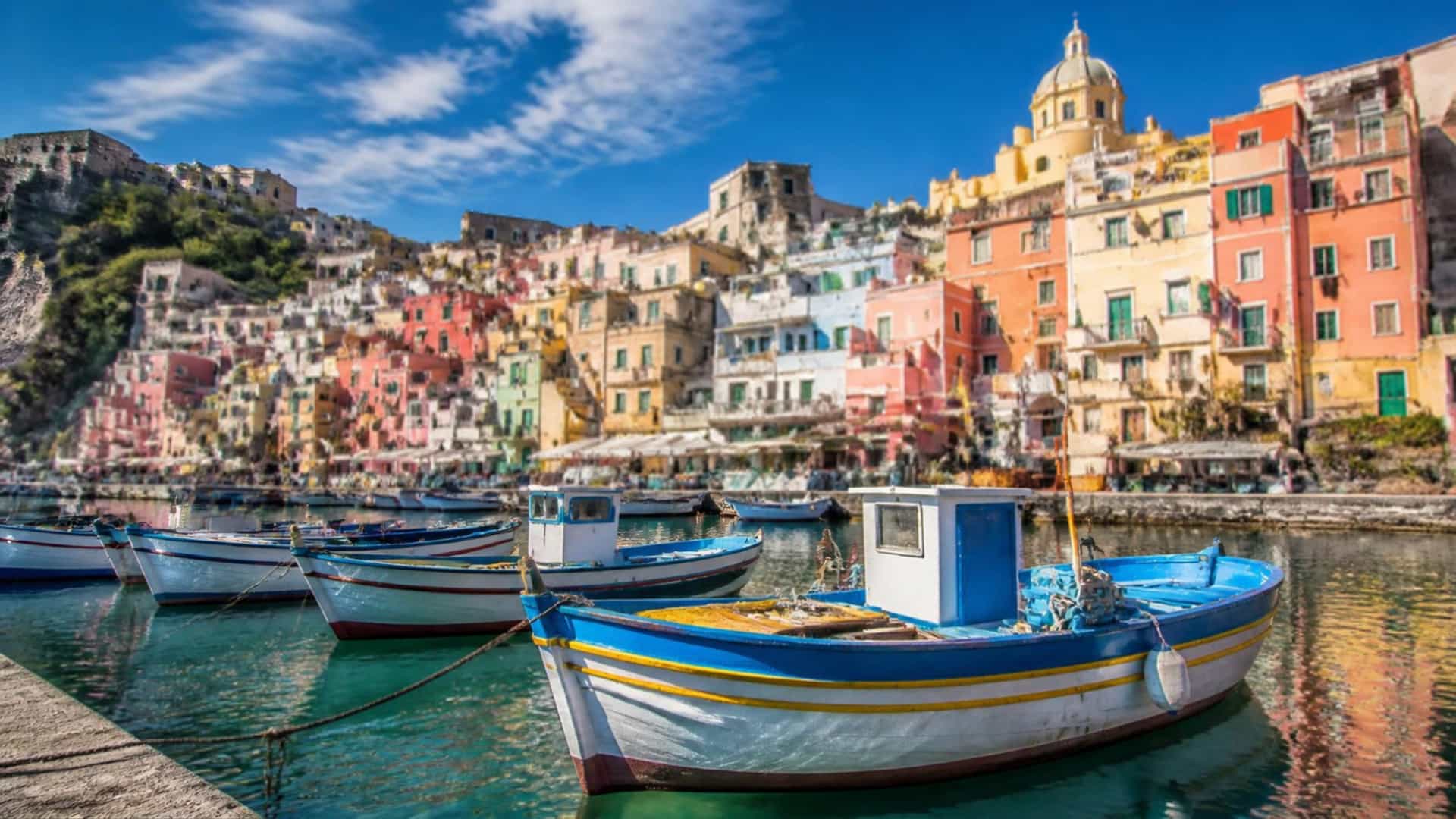 The colorful Mediterranean harbor of Carloforte on San Pietro island, Sardinia, Italy, with pastel houses and traditional fishing boats.