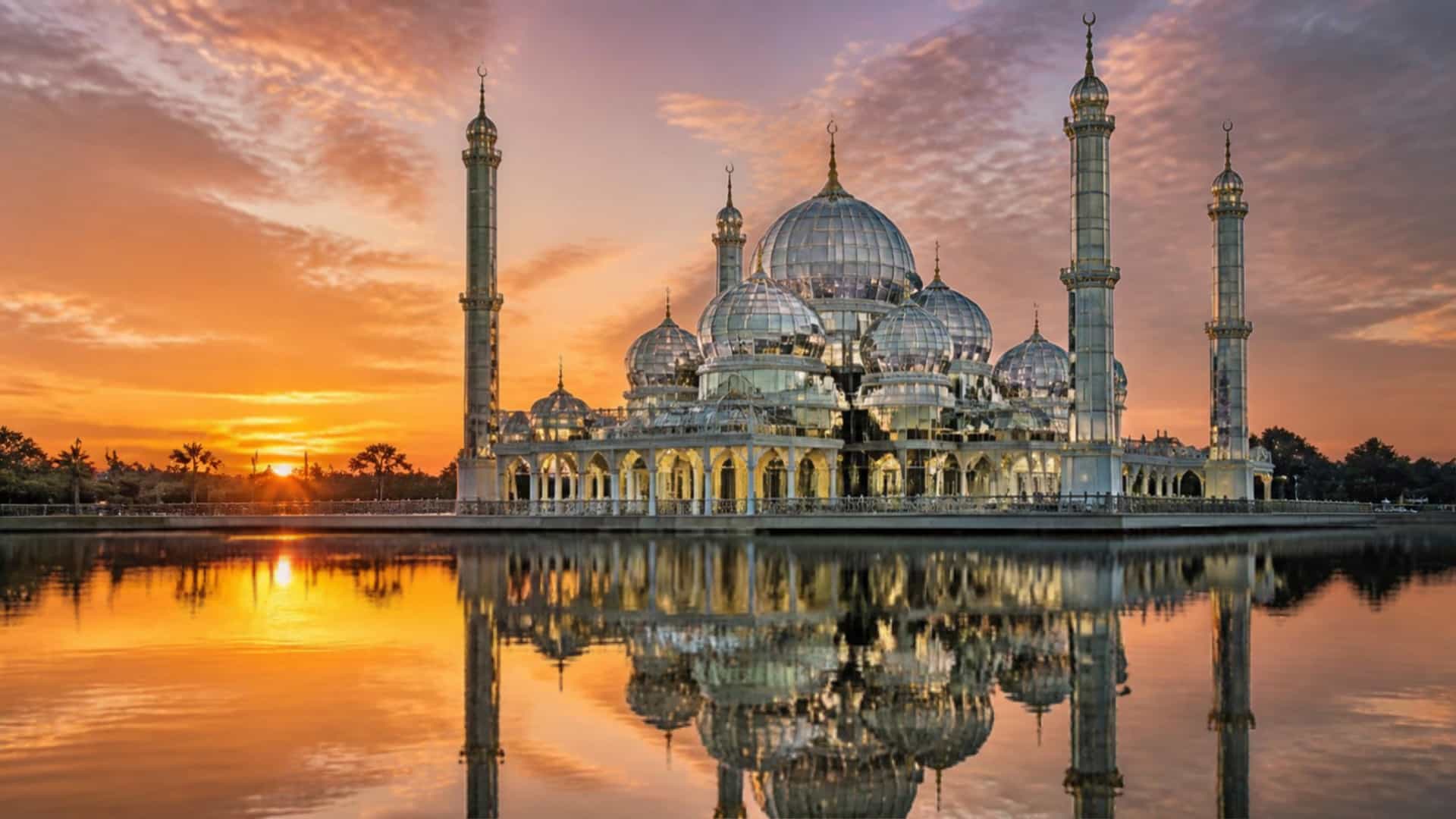 The elegant Crystal Mosque with Islamic architecture reflected on the waterfront at sunset in Kuala Terengganu, Malaysia.