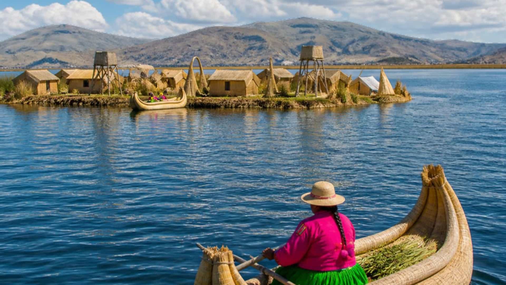 The vast high-altitude Lake Titicaca, Peru, with traditional Uros reed islands and reed boats under a bright Andean sky.