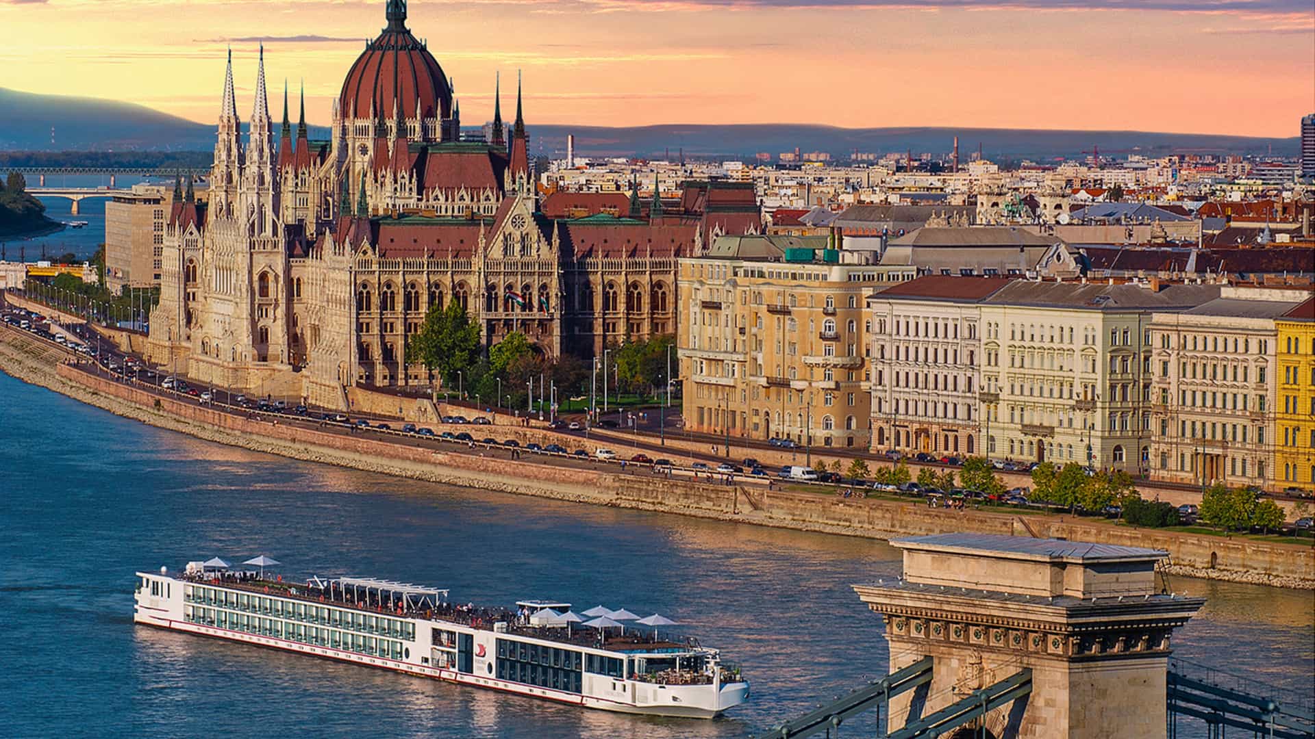 Viking long ship sails through Budapest, Hungary with a glowing skyline and city in the background.
