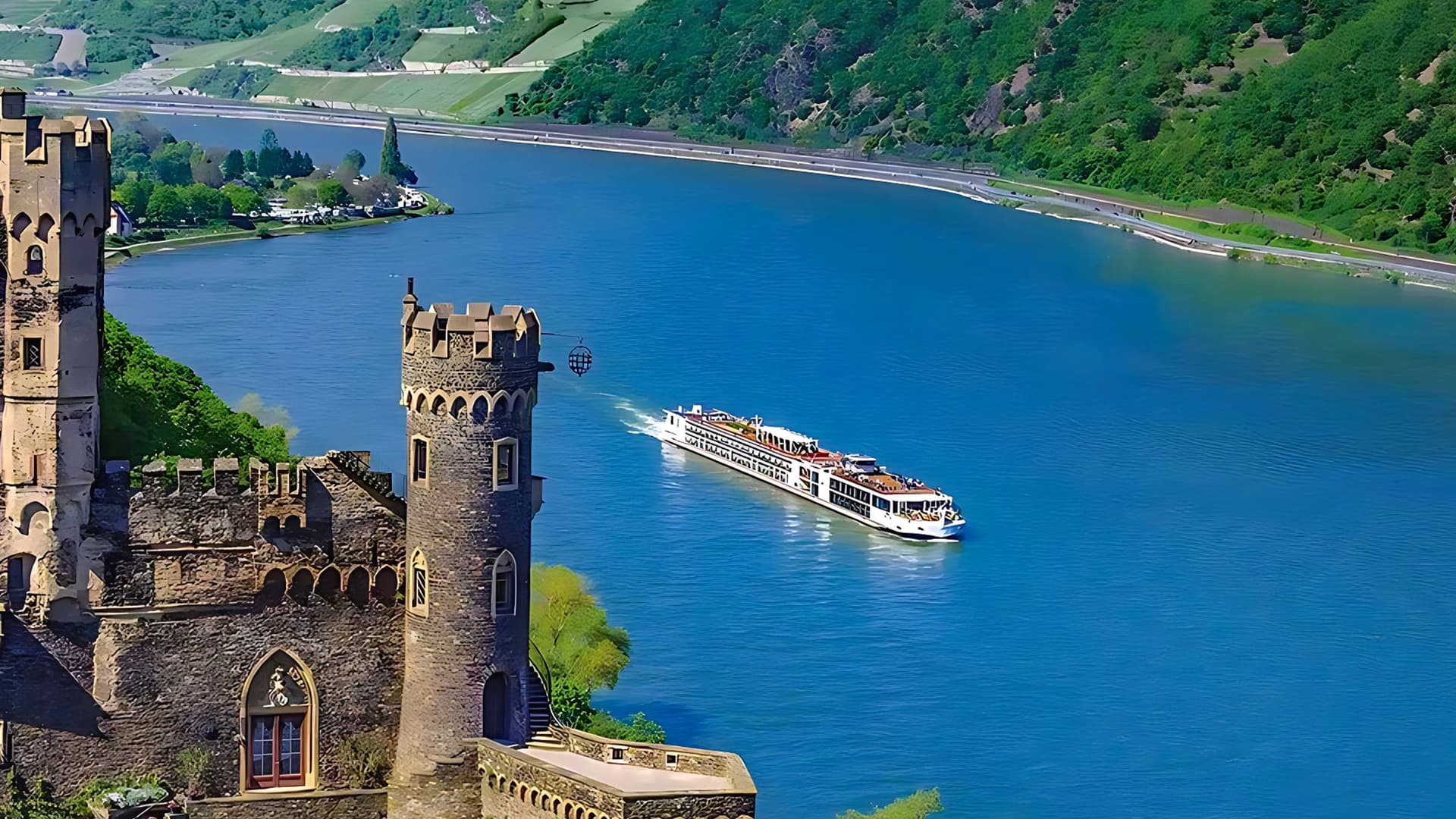 Aerial of Viking Hervor sailing a European river with a castle in the foreground.