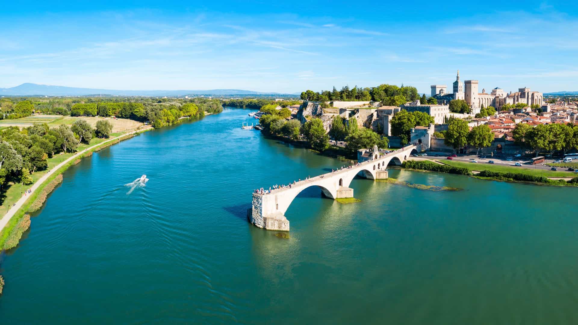 The historic city of Avignon, France, with the famous Pont d'Avignon bridge and the Palais des Papes, seen from the Rhône River, a beautiful stop on a Viking River cruise.